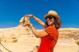 A tourist in a red dress, pyramids behind, Egypt