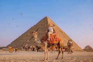 Tourist riding camel near Giza pyramid