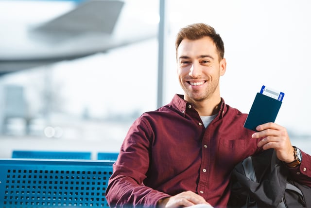 Cheerful Traveller Holding Passport At Airport